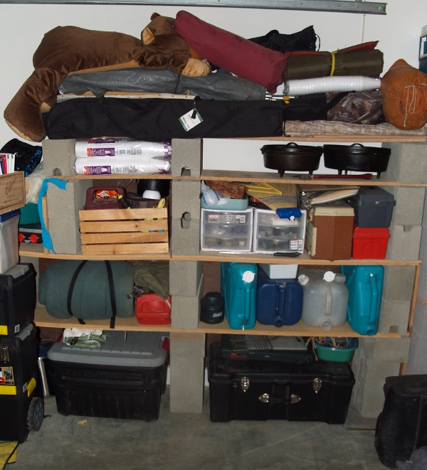 home made shelving to store camp gear on made out of planks of wood and bricks